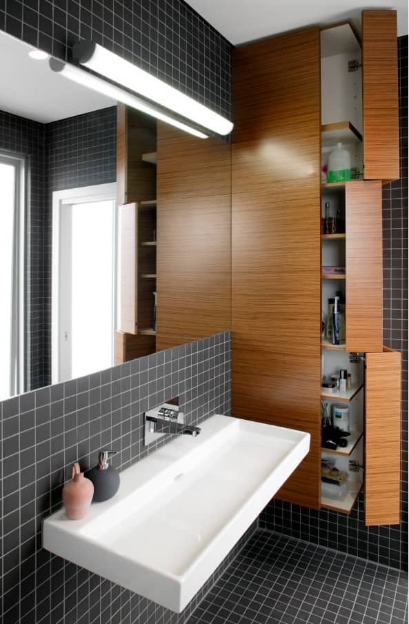 Perfect combination of shallow black tiles and wooden furniture fronts in urban style bathroom 