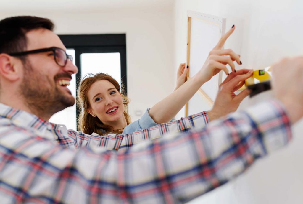 Couple measuring to hang a canvas print.