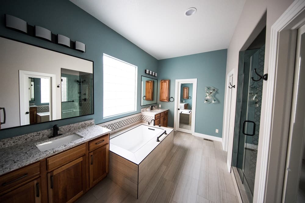 5 Reasons Why Wooden Cabinets Are Best for Your Bathroom. Blue walls and a bathtub with individual wooden trim